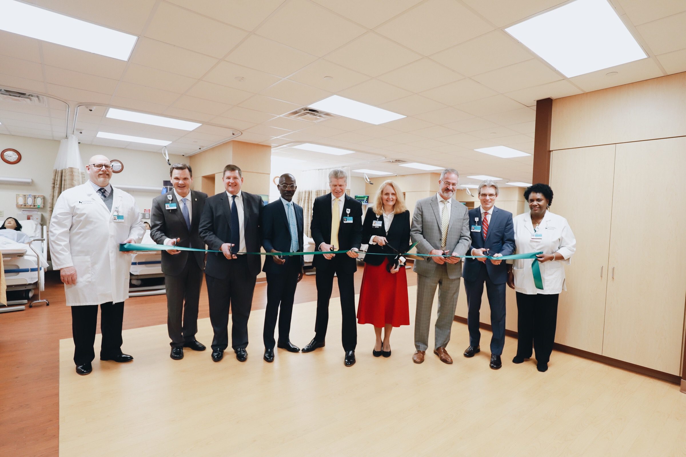 Kettering Medical Center executive leadership, Kettering College board members and Kettering College staff and faculty smile for the camera before the ribbon cutting ceremony, revealing the new IPE Sim Center renovations.